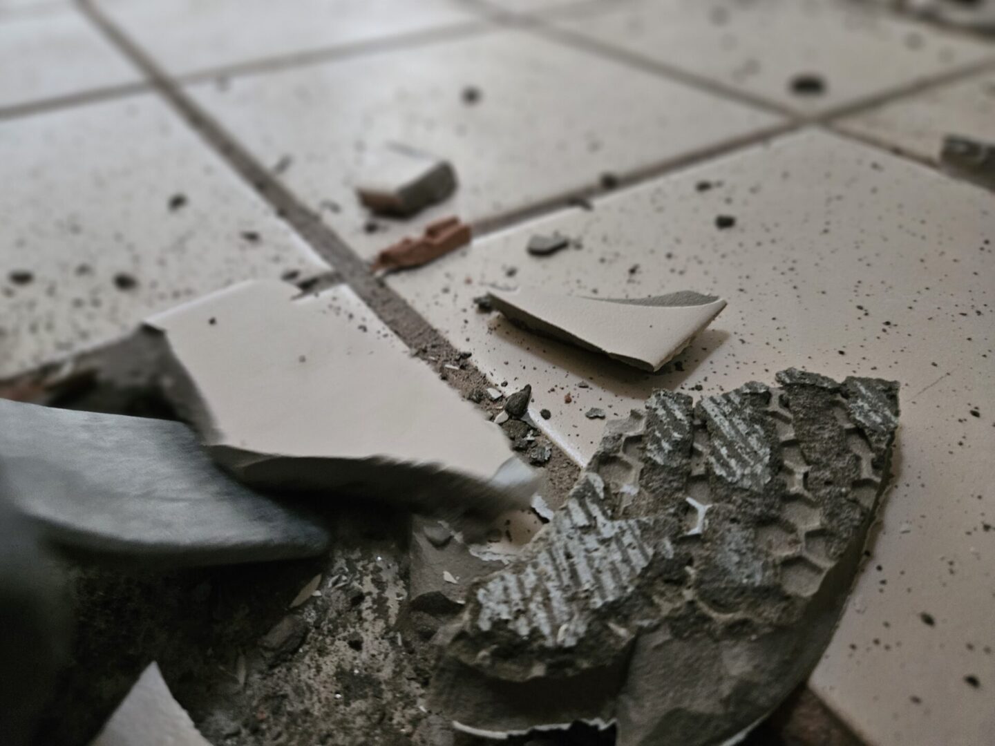 A broken tile floor with pieces of glass