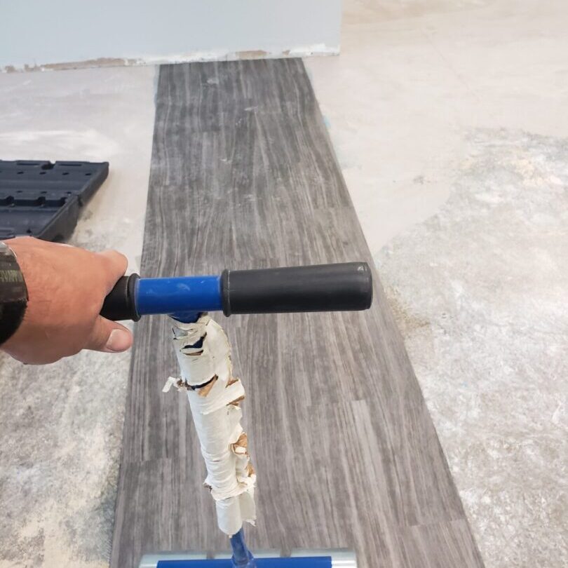 A person using a tool to cut the floor.