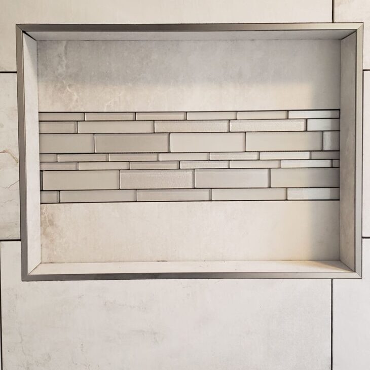 A white tiled wall with a shelf in the middle