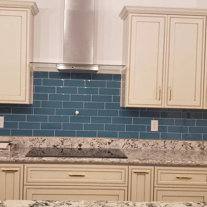 A kitchen with blue tile and white cabinets